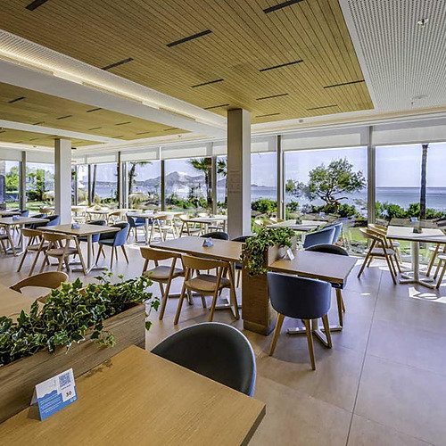 Restaurante con vistas al mar, mesas de madera y sillas azules. Ideal para tu Playa Esperanza Resort.