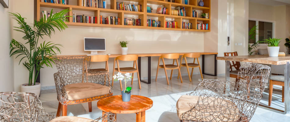 Estudio y área de lectura con estanterías, escritorios y plantas, ideal para Playa Esperanza Resort.