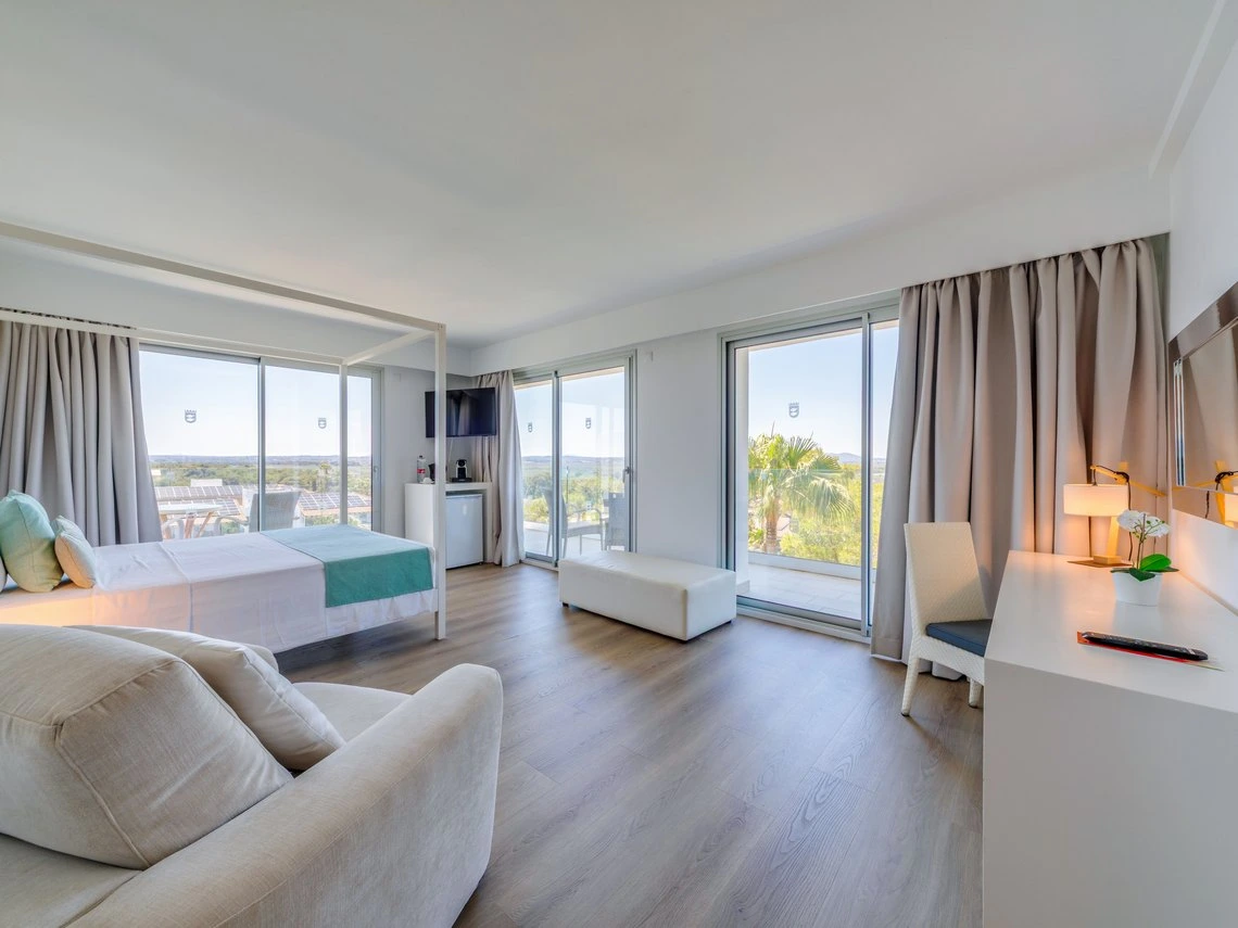 Habitación de hotel moderna con cama Playa Esperanza Resort, balcón y vistas panorámicas al exterior.