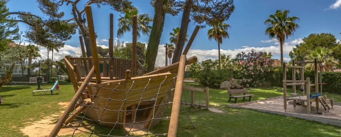 Parque infantil del hotel con juegos de madera, un barco y tobogán. Playa Esperanza Resort