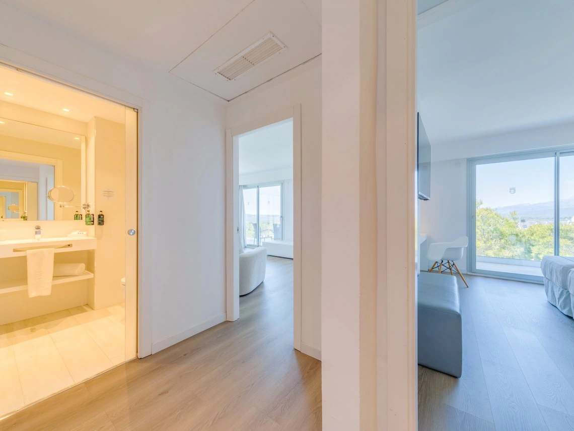 Vista de habitación de hotel con baño moderno, sala de estar y ventana panorámica. Playa Esperanza Resort