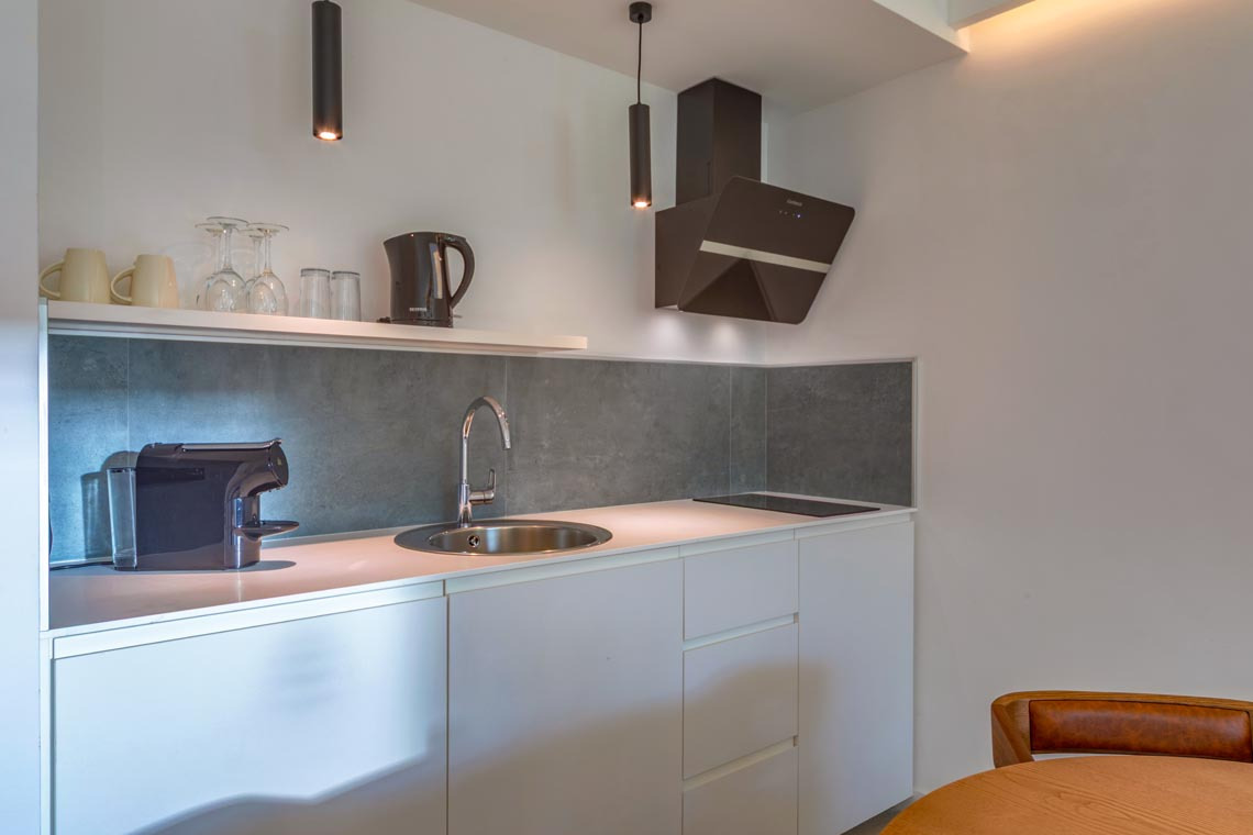 Cocina moderna con cafetera, fregadero y campana extractora. Ideal para preparar tu Playa Esperanza Resort.