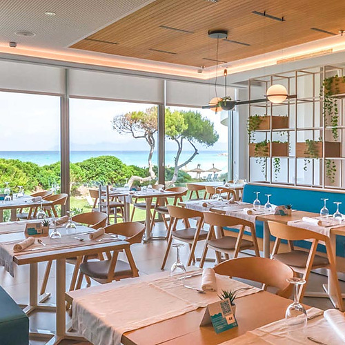 Restaurante de hotel Playa Esperanza Resort con vistas al mar y decoración moderna con plantas.