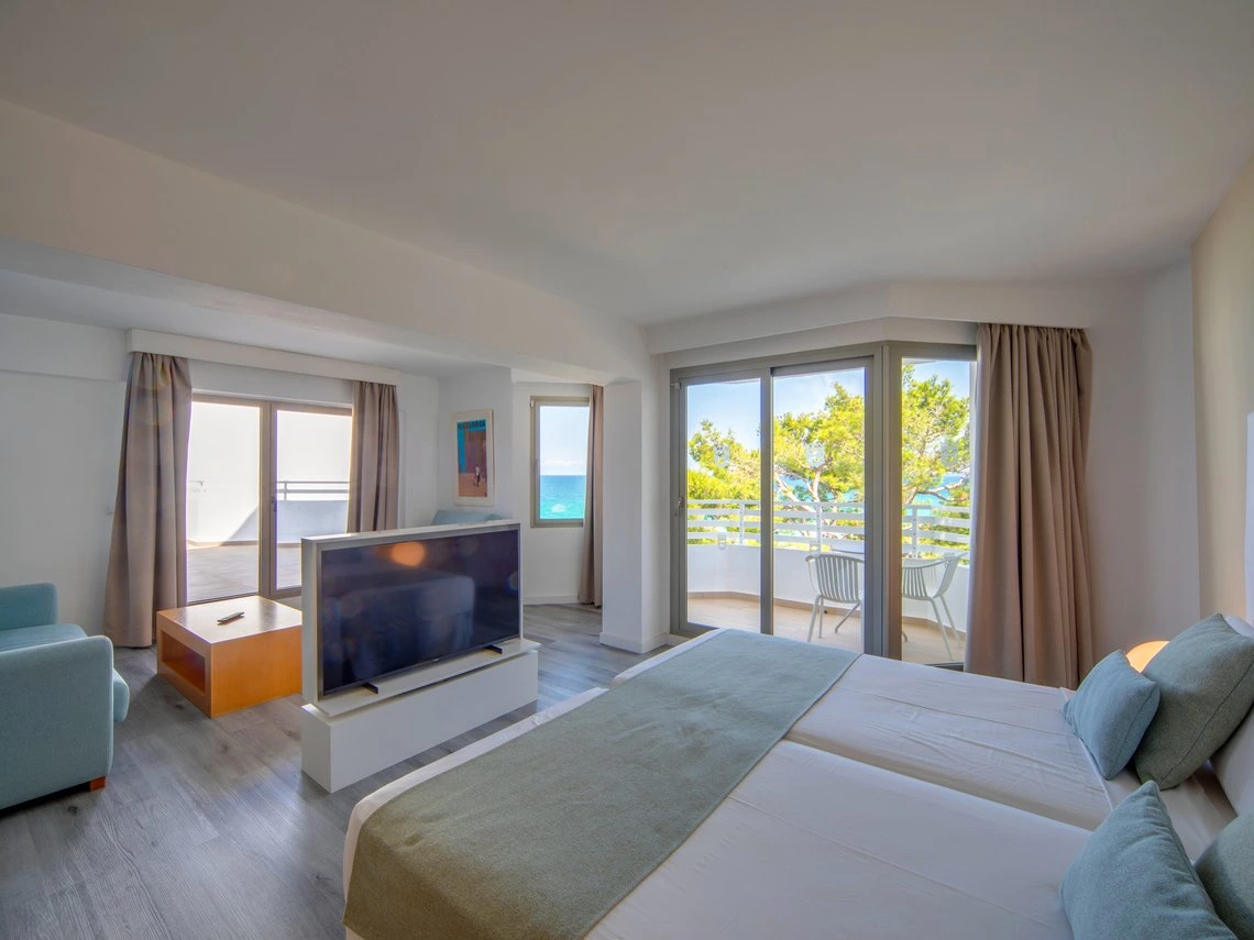 Amplia suite de hotel con vista al mar, dos camas, balcón y Playa Esperanza Resort.