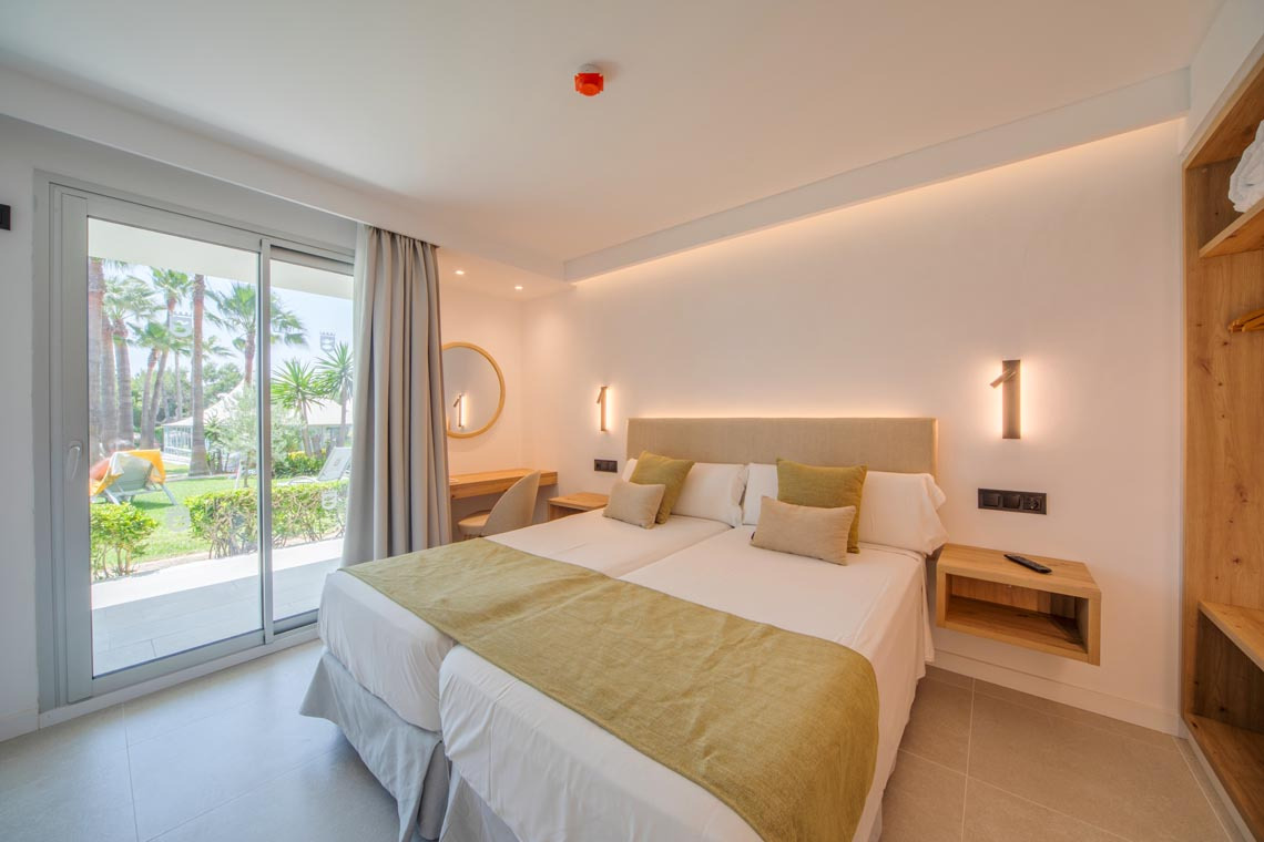 Habitación de hotel doble con vistas al jardín,Playa Esperanza Resort, y mobiliario moderno.