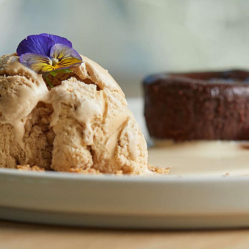 Pastel de chocolate con helado de café y flores comestibles, perfecto paraPlaya Esperanza Resort.