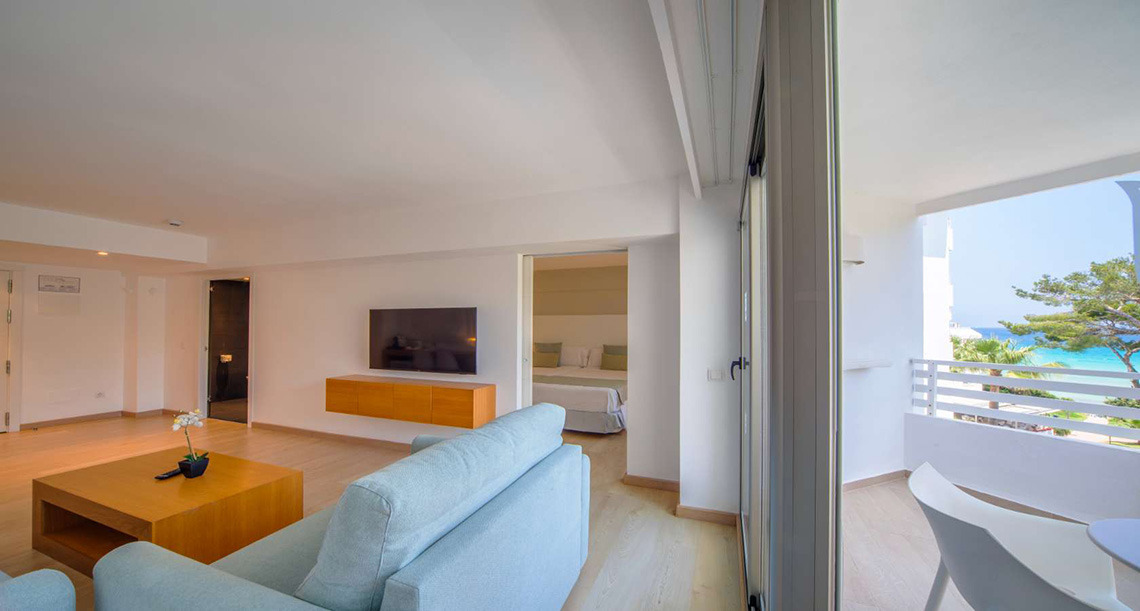 Playa Esperanza Resort: sala de estar luminosa con sofá azul y balcón con vistas al mar y la playa.