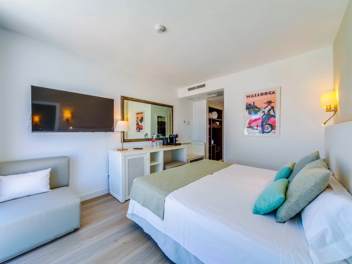 Habitación de hotel moderna con cama confortable, TV y decoración temática Playa Esperanza Resort.