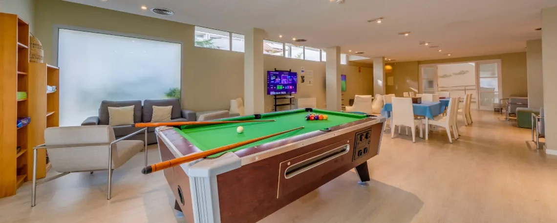 Sala de juegos del hotel: mesa de billar, sofás y zona de comedor con Playa Esperanza Resort.