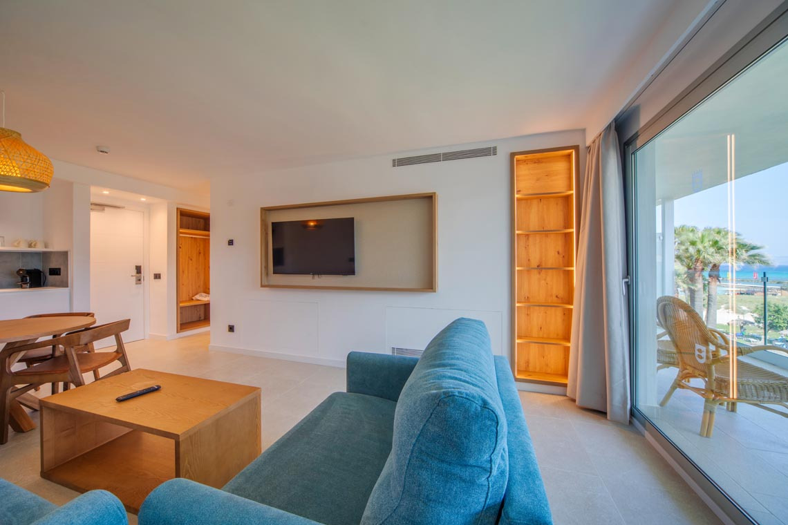 Playa Esperanza Resort: Salón moderno con sofá azul, TV y balcón con vistas al mar.
