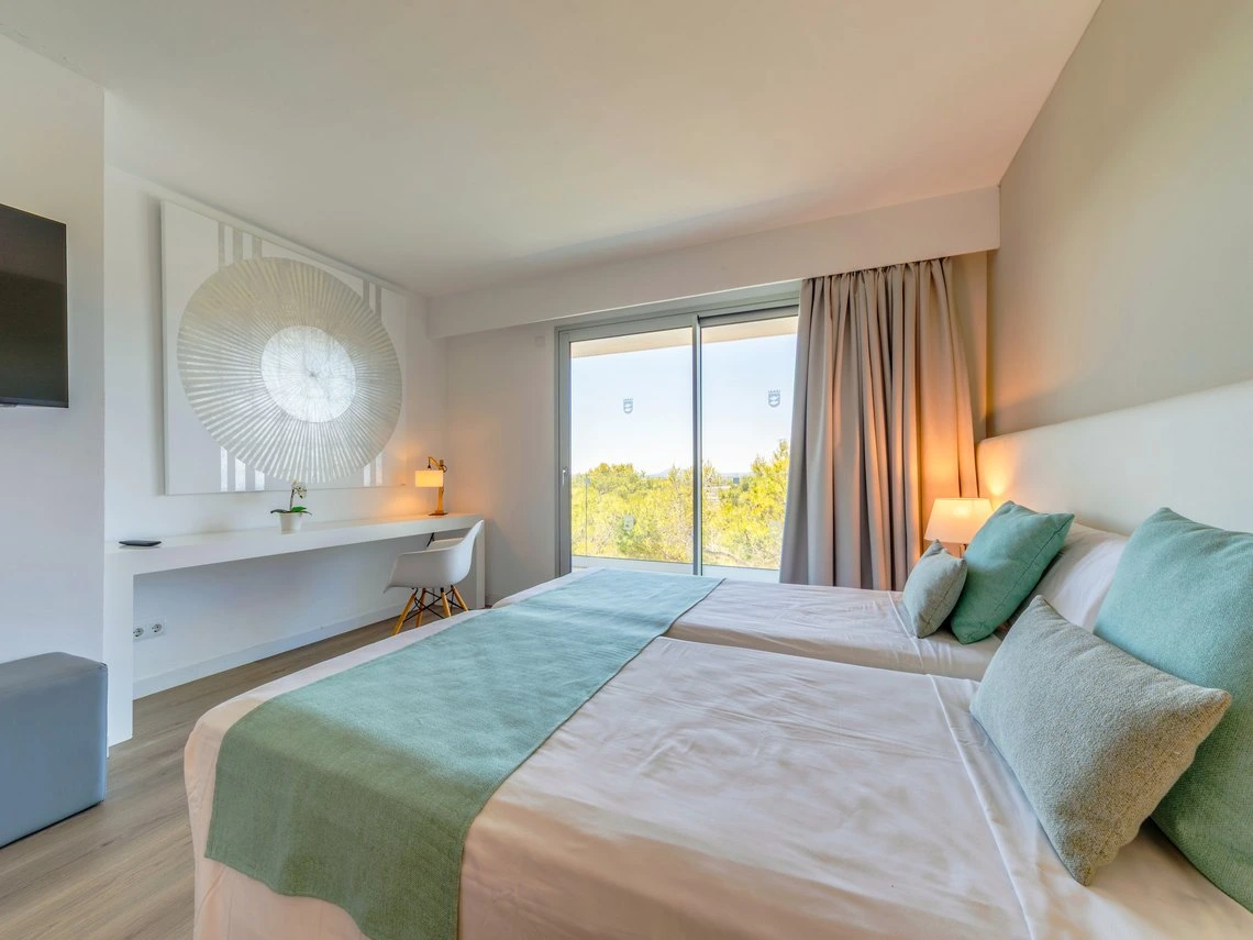 Habitación de hotel moderna con dos camas, escritorio y vista al exterior. Playa Esperanza Resort