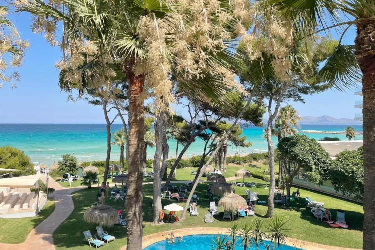 Playa Esperanza Resort: Piscina y playa con palmeras, tumbonas y gente relajándose.