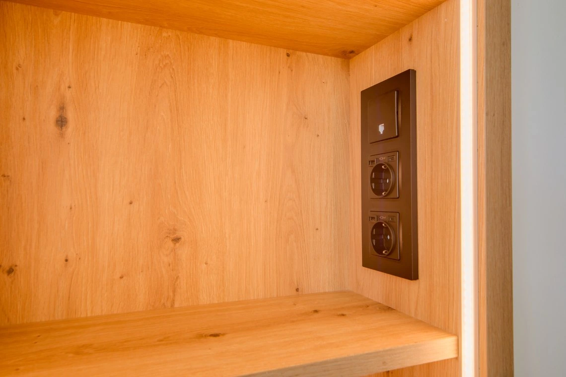 Enchufe moderno y luz LED en madera natural, ideal para tu habitación de hotel. Playa Esperanza Resort