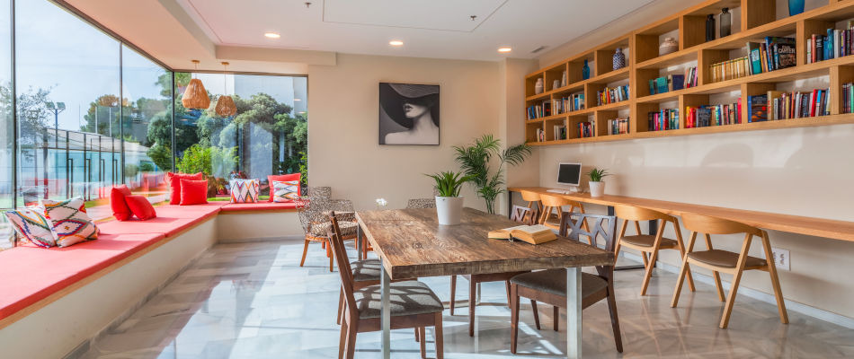 Playa Esperanza Resort: moderna sala comunitaria con sofás, mesa y estanterías de libros.