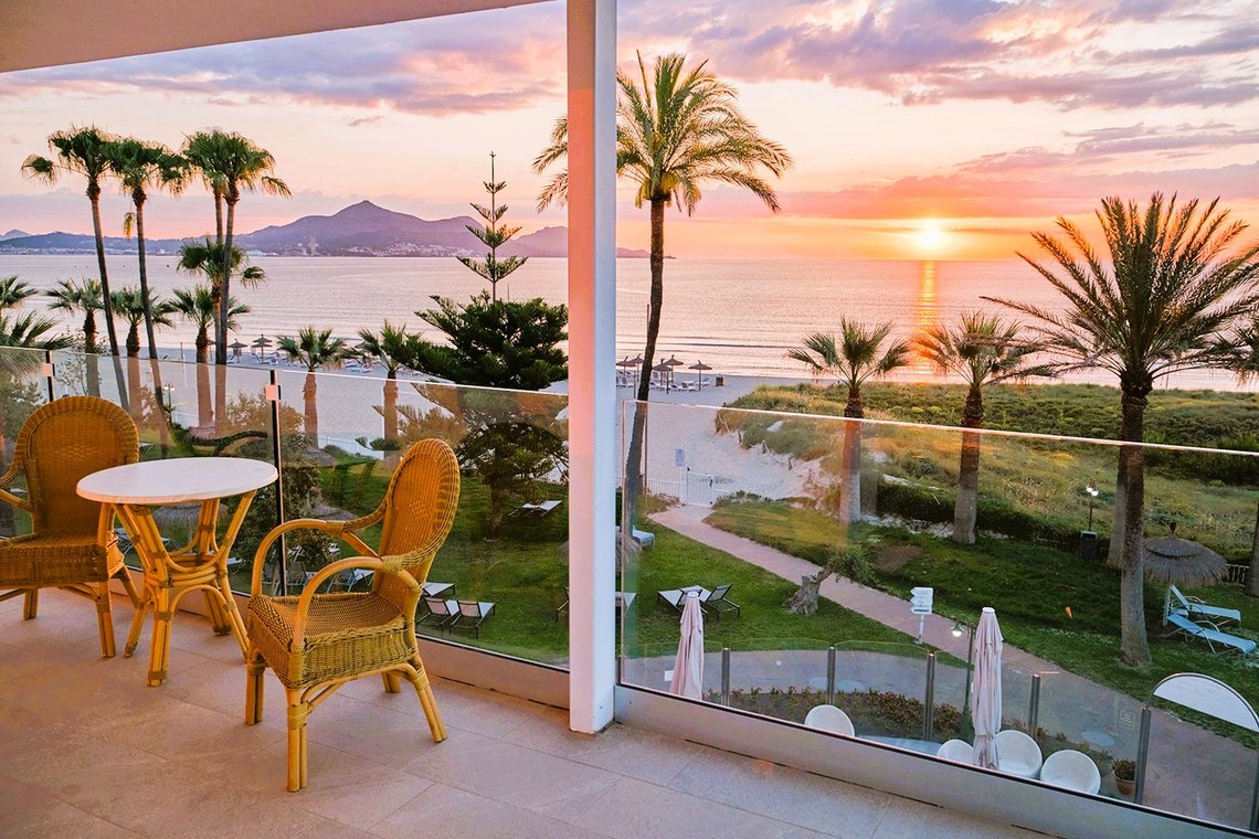 Balcón con vista al mar y palmeras al atardecer, ideal para tu Playa Esperanza Resort.