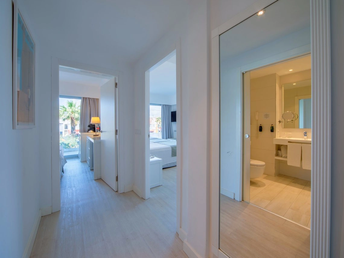 Pasillo de hotel con puertas a habitaciones y baño, espejo grande. Playa Esperanza Resort.
