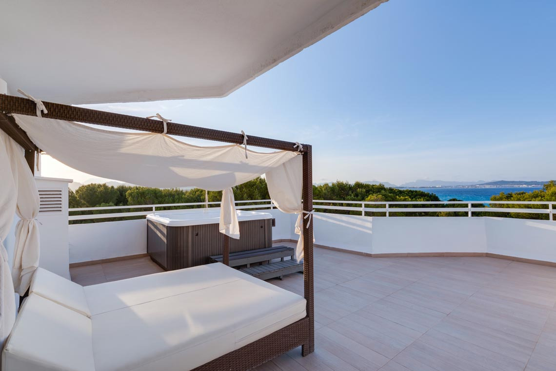 Terraza de hotel con jacuzzi, cama balinesa y vista al mar, perfecta paraPlaya Esperanza Resort.