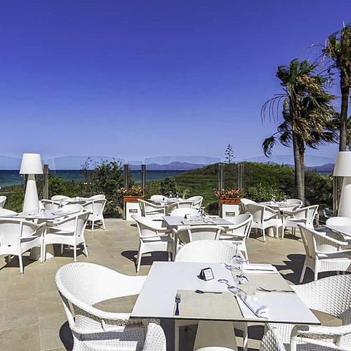 Mesas en terraza de hotel frente al mar, ideal para Playa Esperanza Resort.