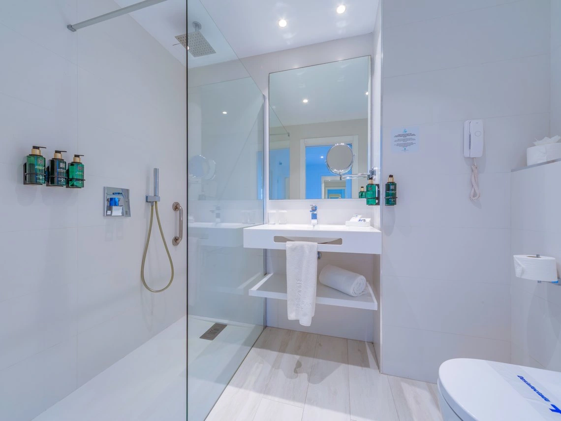 Baño moderno con ducha espaciosa, lavabo y artículos de aseo. Playa Esperanza Resort