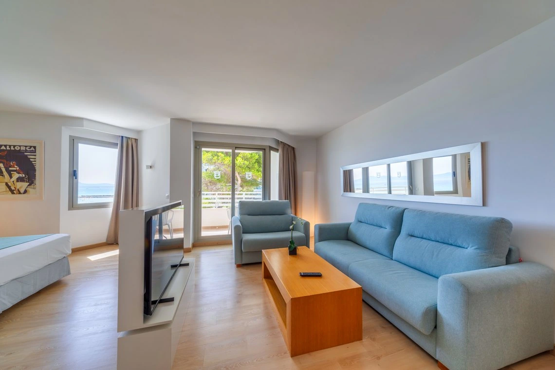 Habitación moderna con vista al mar, sofá Playa Esperanza Resort, TV y cama.