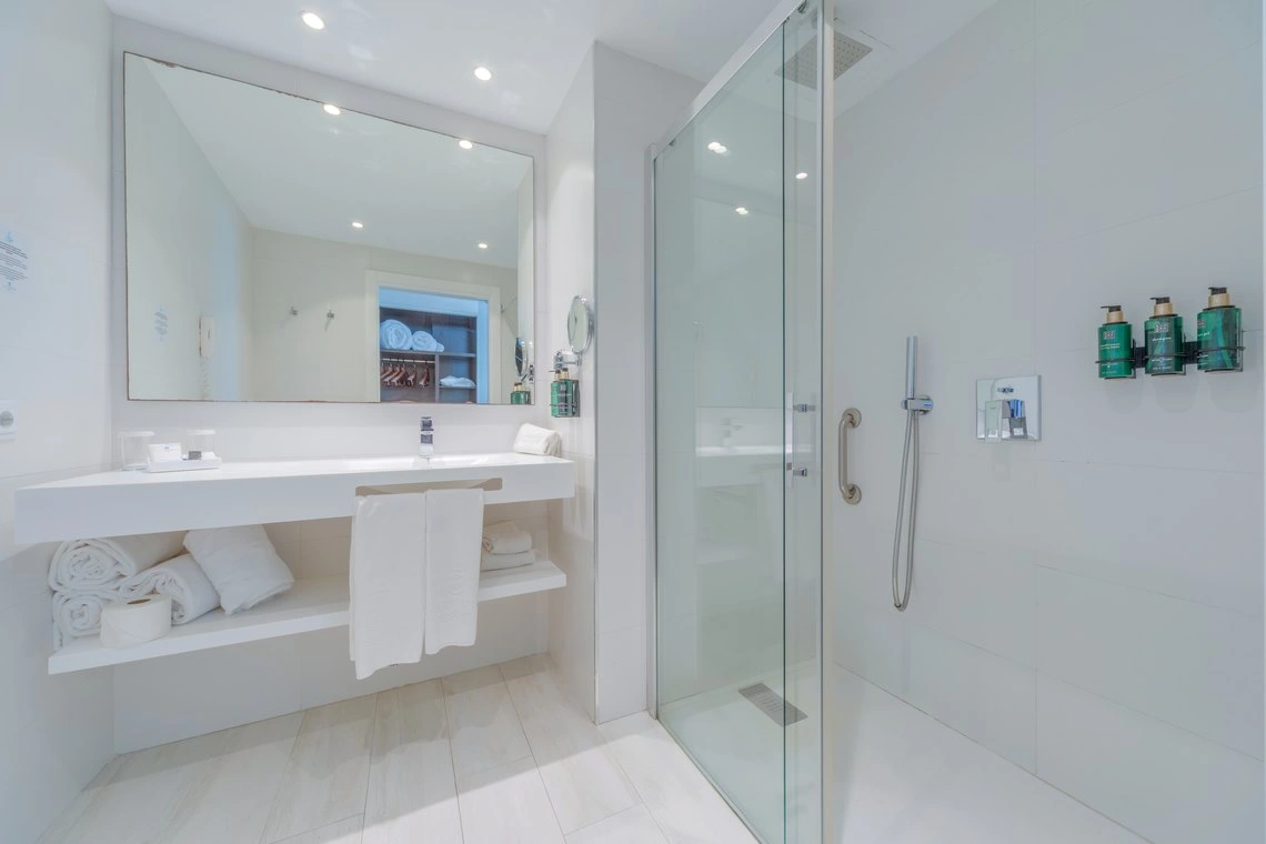 Baño moderno con ducha de cristal y Playa Esperanza Resort.