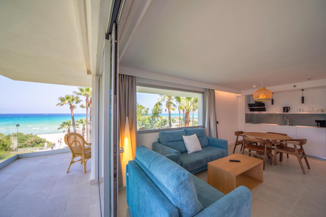 Playa Esperanza Resort: Sala de estar azul luminosa con vista a la playa, balcón y cocina moderna.