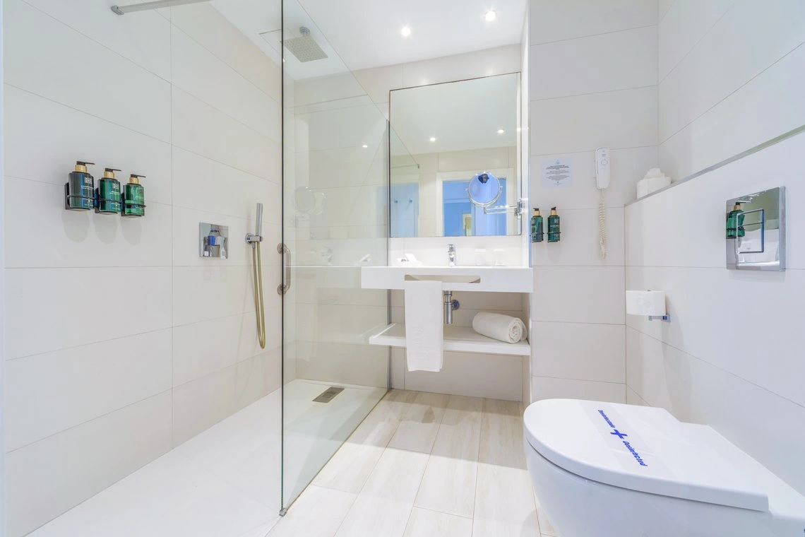 Baño moderno con ducha, inodoro y lavabo. Playa Esperanza Resort en hotel limpio.