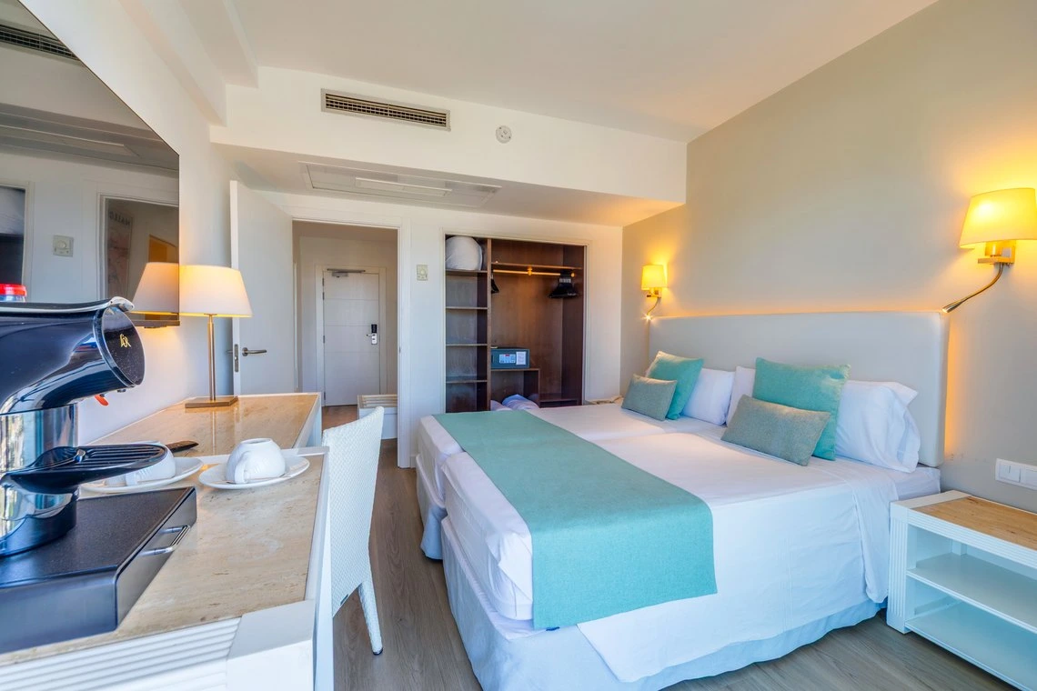 Habitación de hotel moderna con cama doble, cafetera y vista a la armario. Playa Esperanza Resort