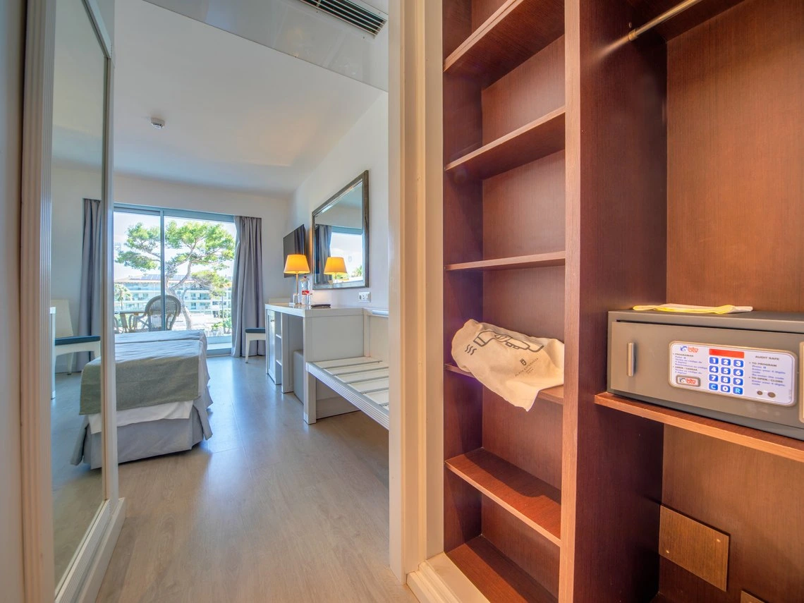 Armario con caja fuerte, toalla y perchero en habitación de hotel con vista al exterior, Playa Esperanza Resort.
