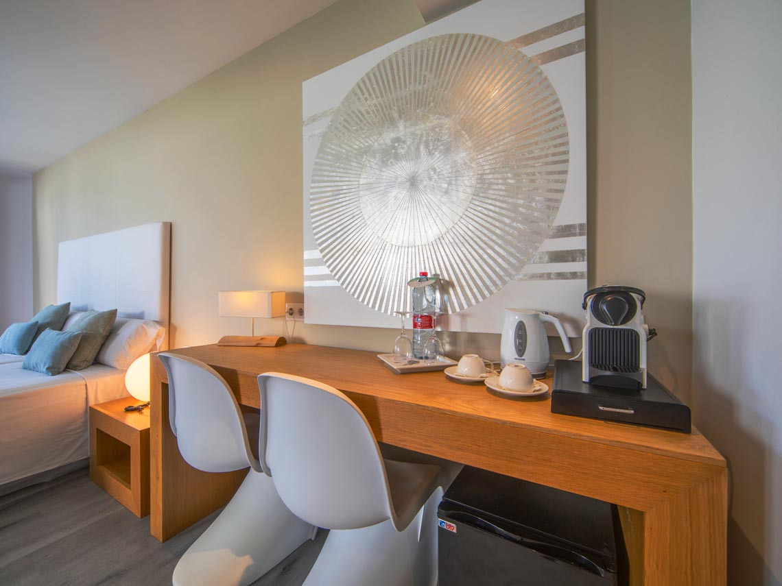 Detalles de la habitación: cafetera Nespresso, tetera, escritorio de madera, asientos y Playa Esperanza Resort.