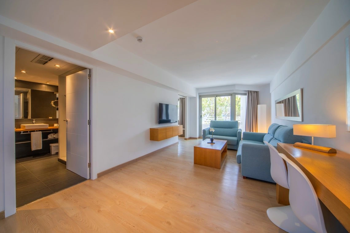 Suite moderna con sala de estar luminosa, baño y balcón. Playa Esperanza Resort