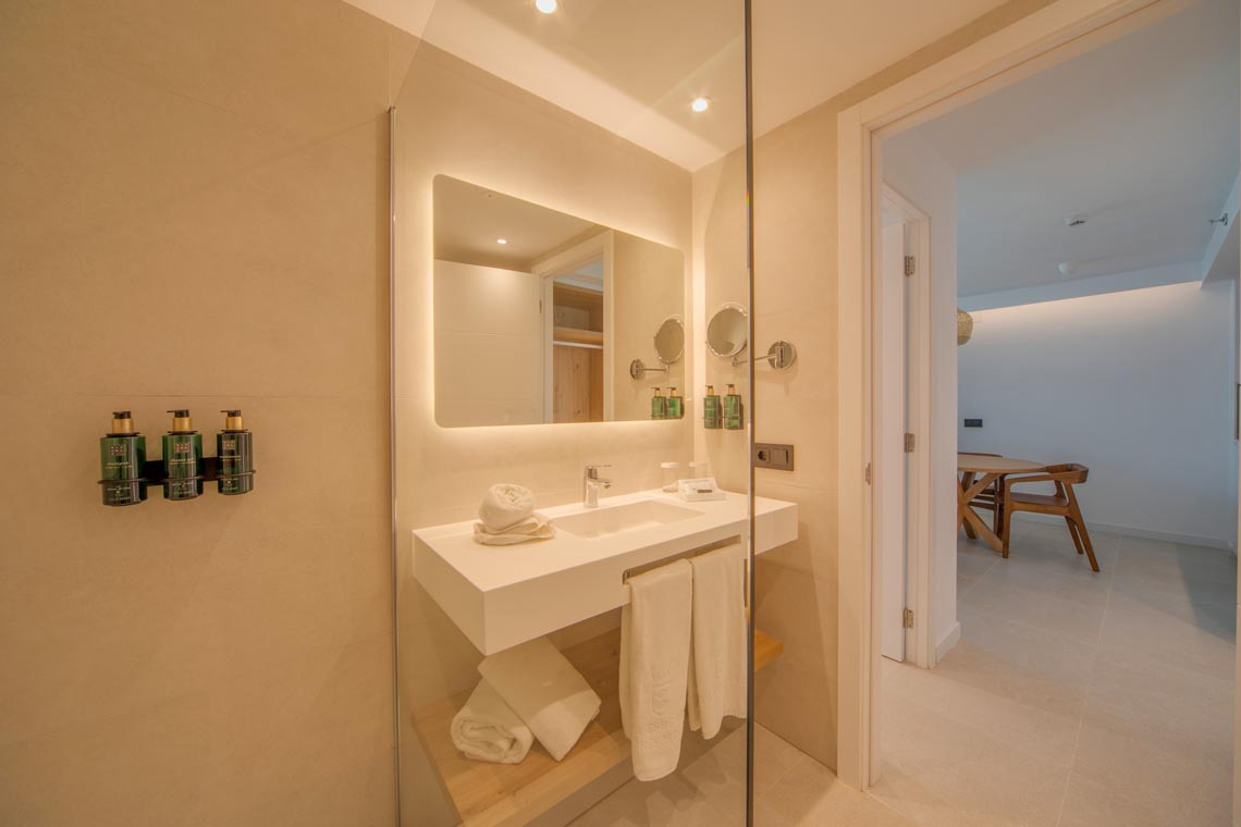 Lujoso baño de hotel con espejo iluminado, lavabo blanco y amenities Playa Esperanza Resort.
