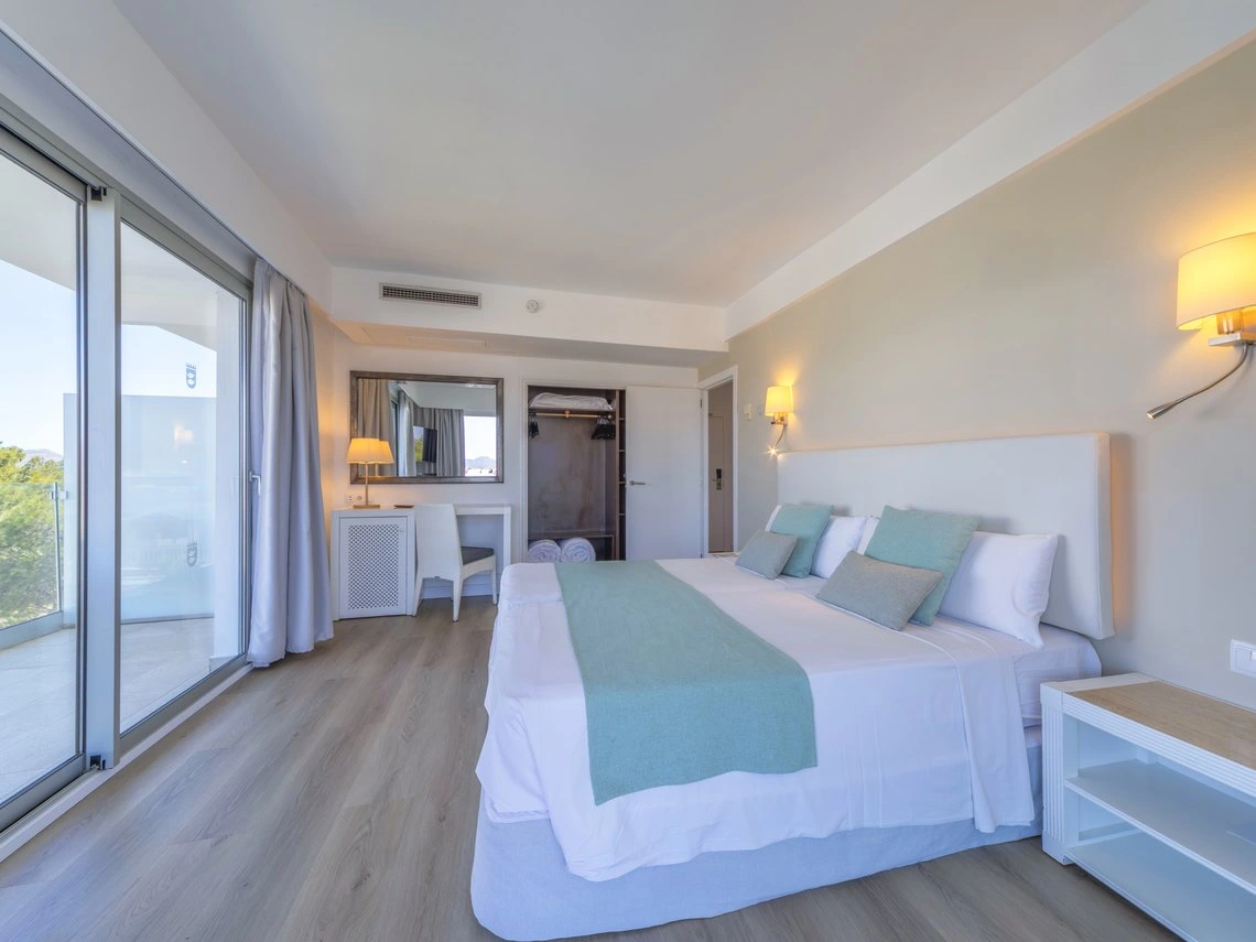 Habitación de hotel con cama grande, Playa Esperanza Resort, balcón y armario abierto.