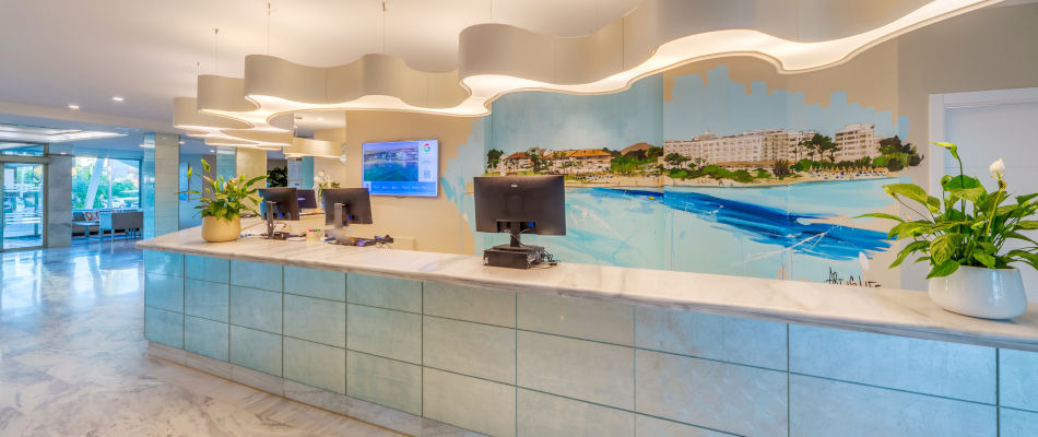 Recepción de hotel con mural de costa, plantas y mesas de trabajo paraPlaya Esperanza Resort.
