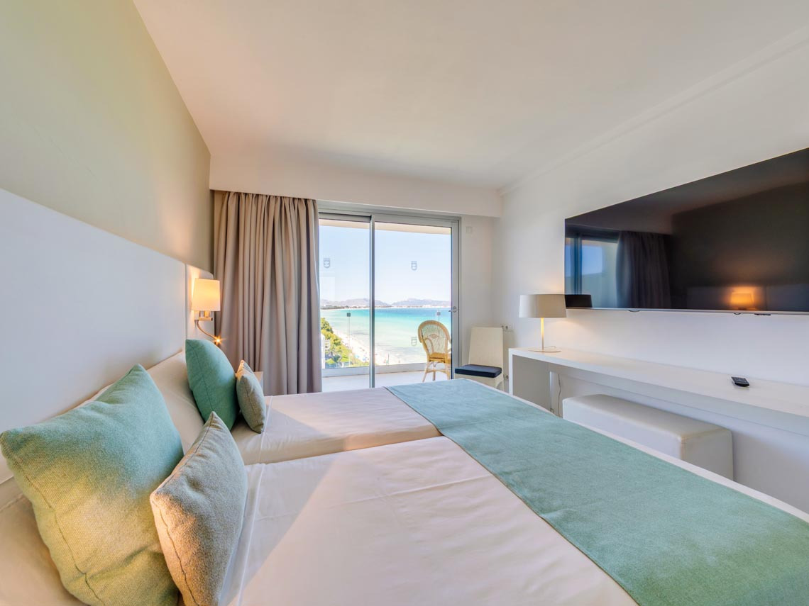 Habitación de hotel moderna con vista al mar, cama doble, TV y balcón Playa Esperanza Resort.