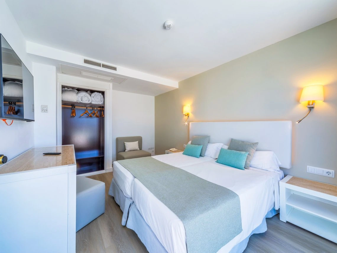 Habitación doble con TV, armario y dos camas, perfecta para tu Playa Esperanza Resort.
