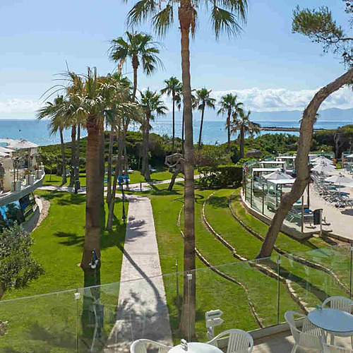 Terraza de restaurantePlaya Esperanza Resort con vistas al mar y piscina, palmeras y sol.