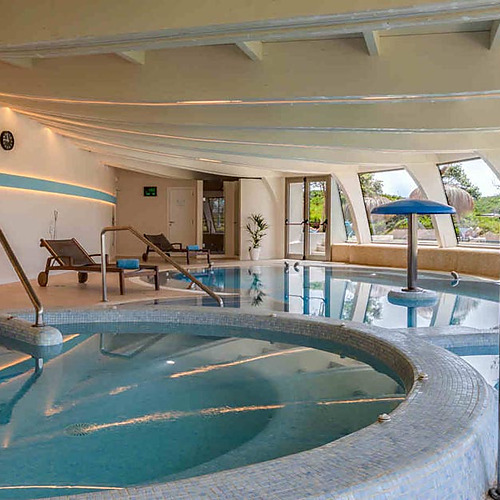 Piscina interior climatizada con tumbonas y vistas al exterior. Playa Esperanza Resort