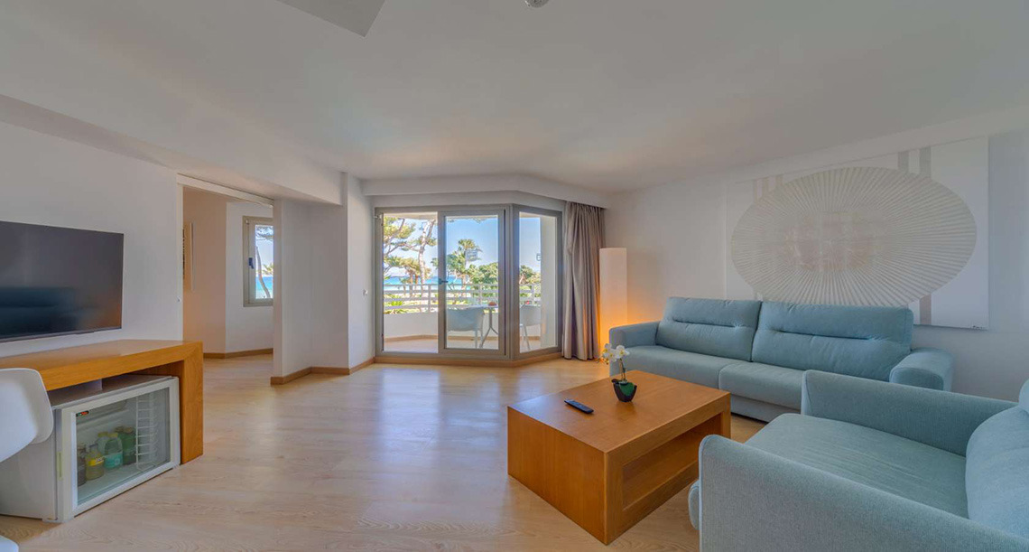 Sofá azul y mesa de centro en sala de estar con vista al mar de hotel. Playa Esperanza Resort