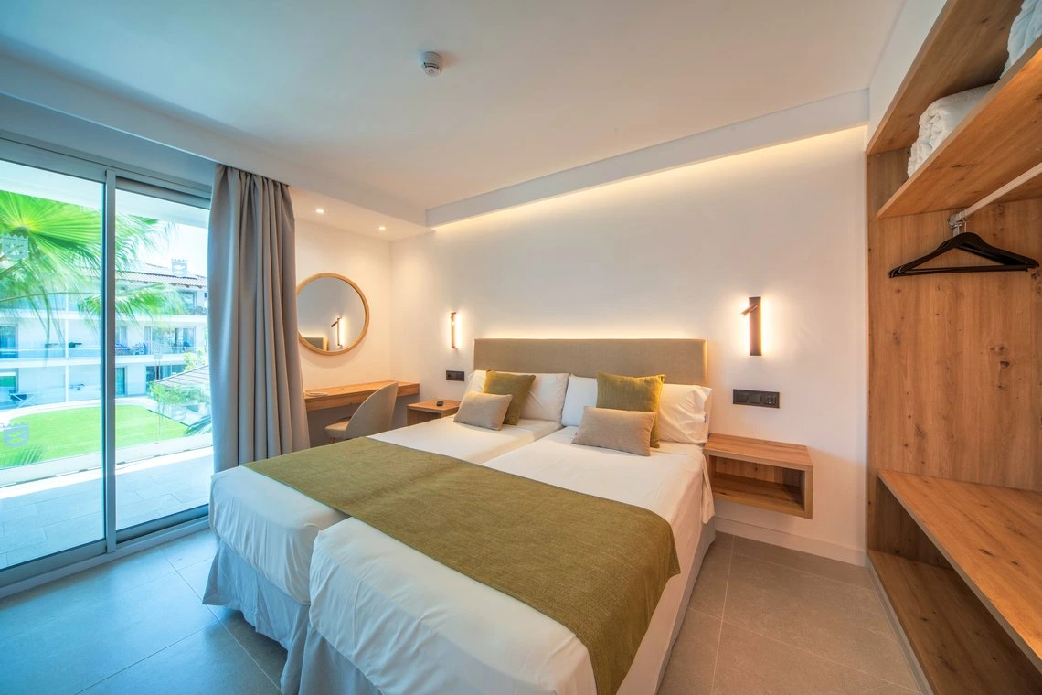 Dormitorio moderno con dos camas y vista al jardín, ideal para Playa Esperanza Resort.