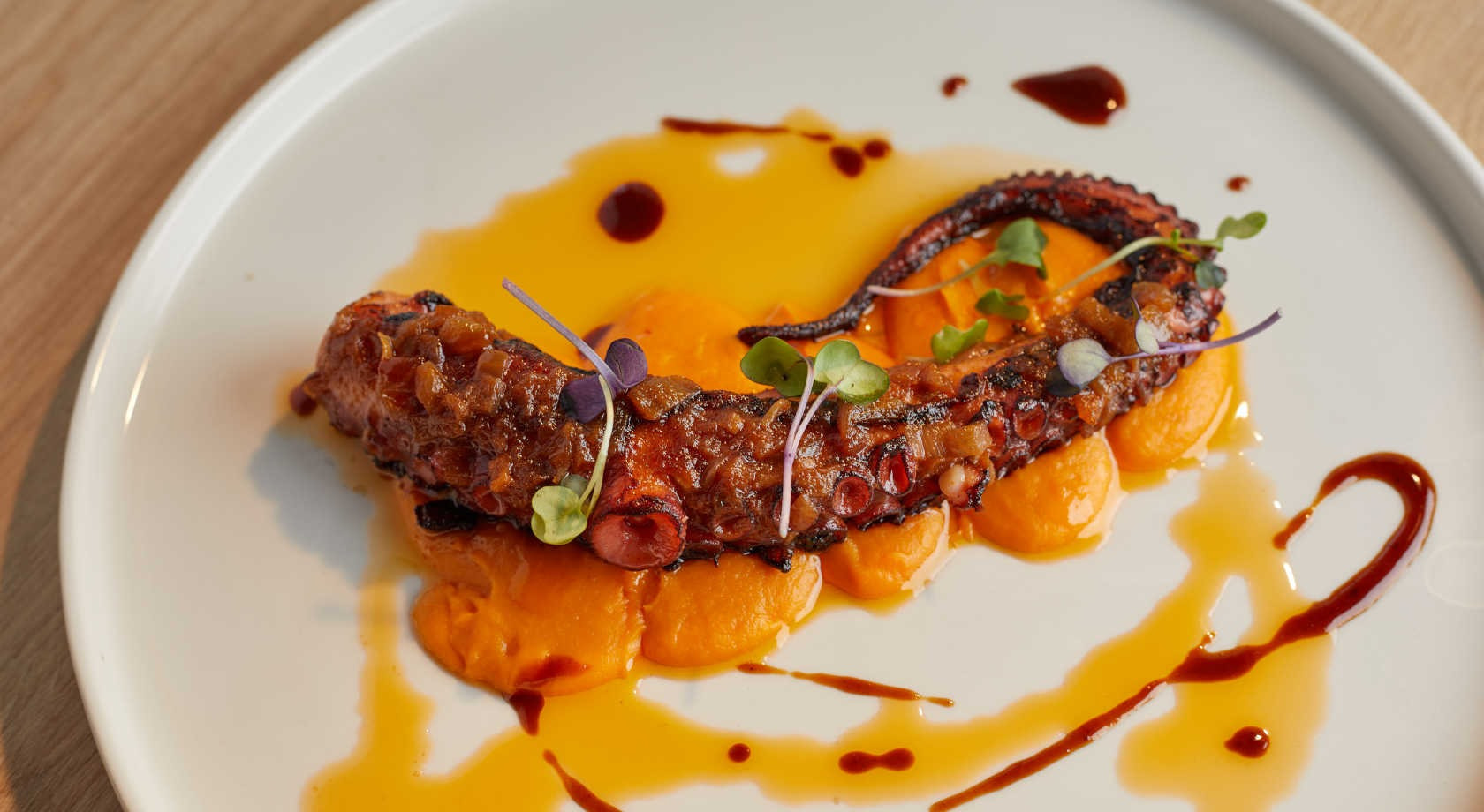 PulpoPlaya Esperanza Resort a la parrilla sobre puré de calabaza, servido en plato blanco.