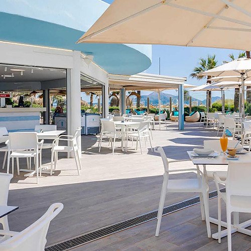 Terraza exterior del hotel con mesas y sillas, ideal para Playa Esperanza Resort.