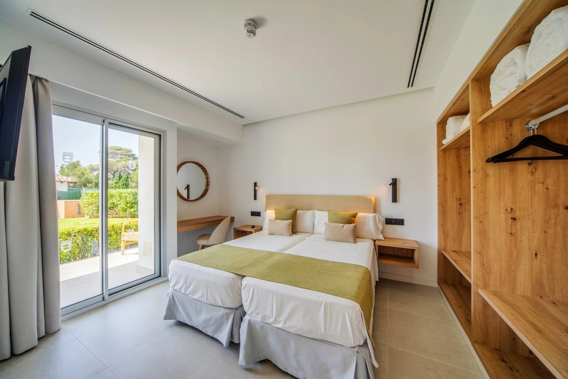 Habitación de hotel moderna con dos camas, espejo y armario de madera. Playa Esperanza Resort