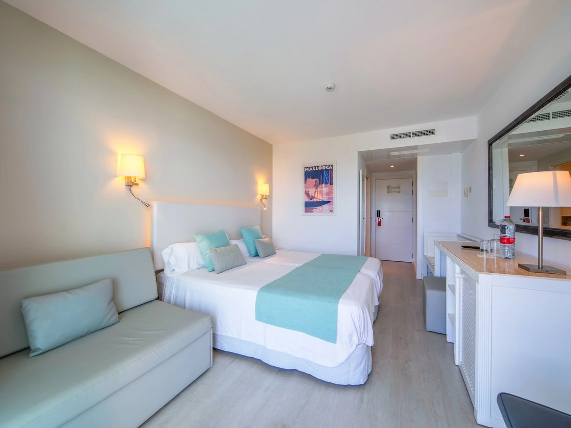 Habitación luminosa con cama doble, sofá y decoración moderna. Playa Esperanza Resort en Mallorca.