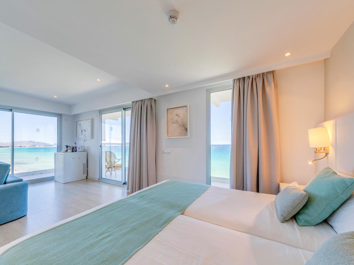 Habitación de hotel con vistas al mar: camas gemelas,Playa Esperanza Resort, balcón, luz natural y decoración moderna.