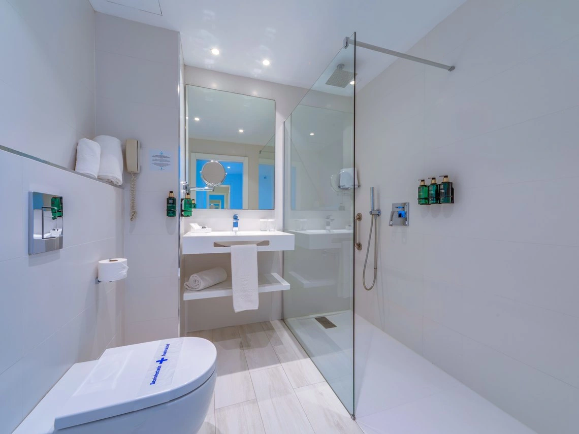 Baño moderno y limpio con ducha y aseo, ideal para Playa Esperanza Resort