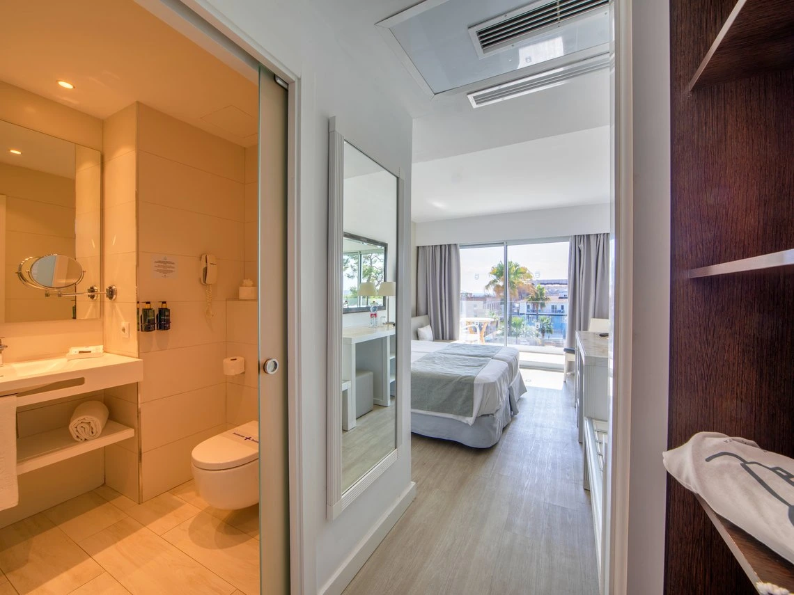 Vista de habitación de hotel moderna con baño y cama, perfecta para tu Playa Esperanza Resort.