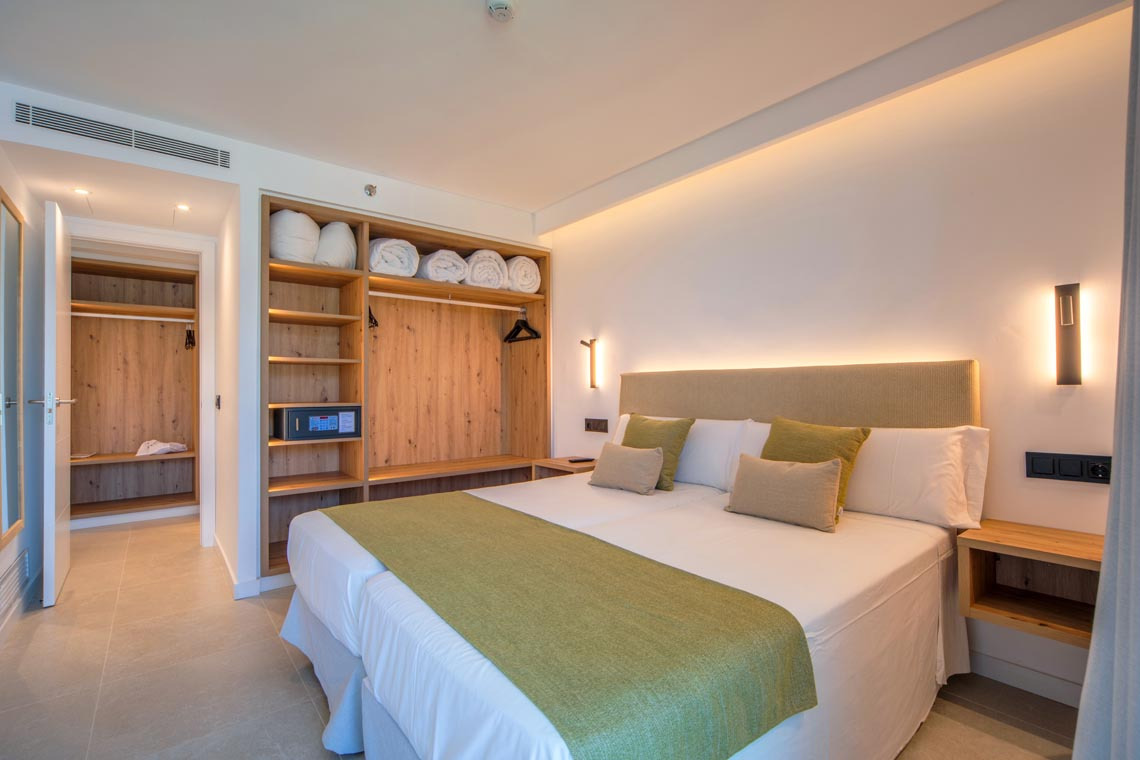 Cama espaciosa en habitación de hotel con armario y Playa Esperanza Resort.