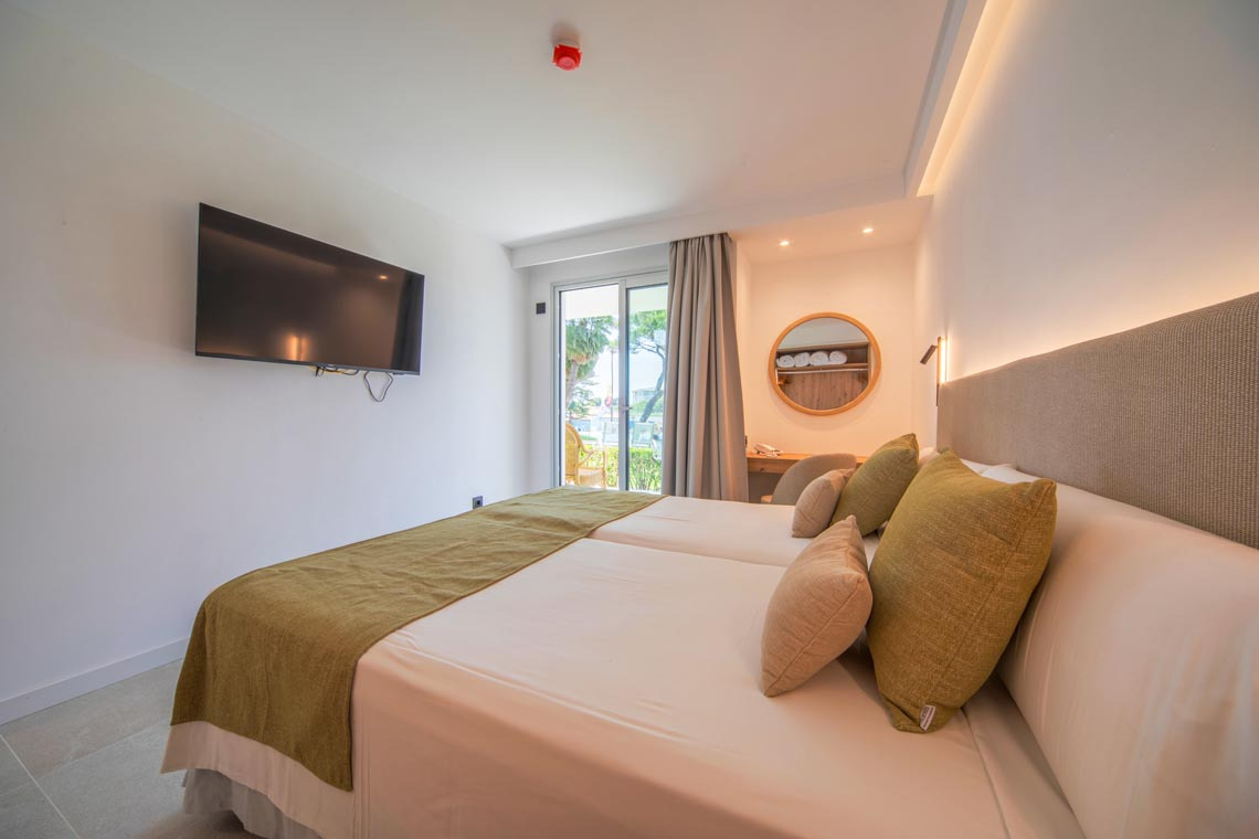 Habitación de hotel con dos camas,Playa Esperanza Resort, TV y ventana al exterior.