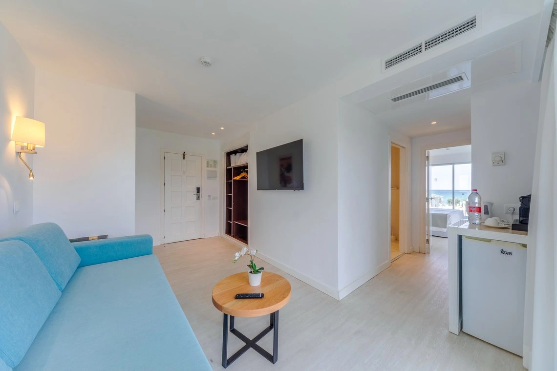 Habitación de hotel moderna con sofá azul y vista al mar. Playa Esperanza Resort